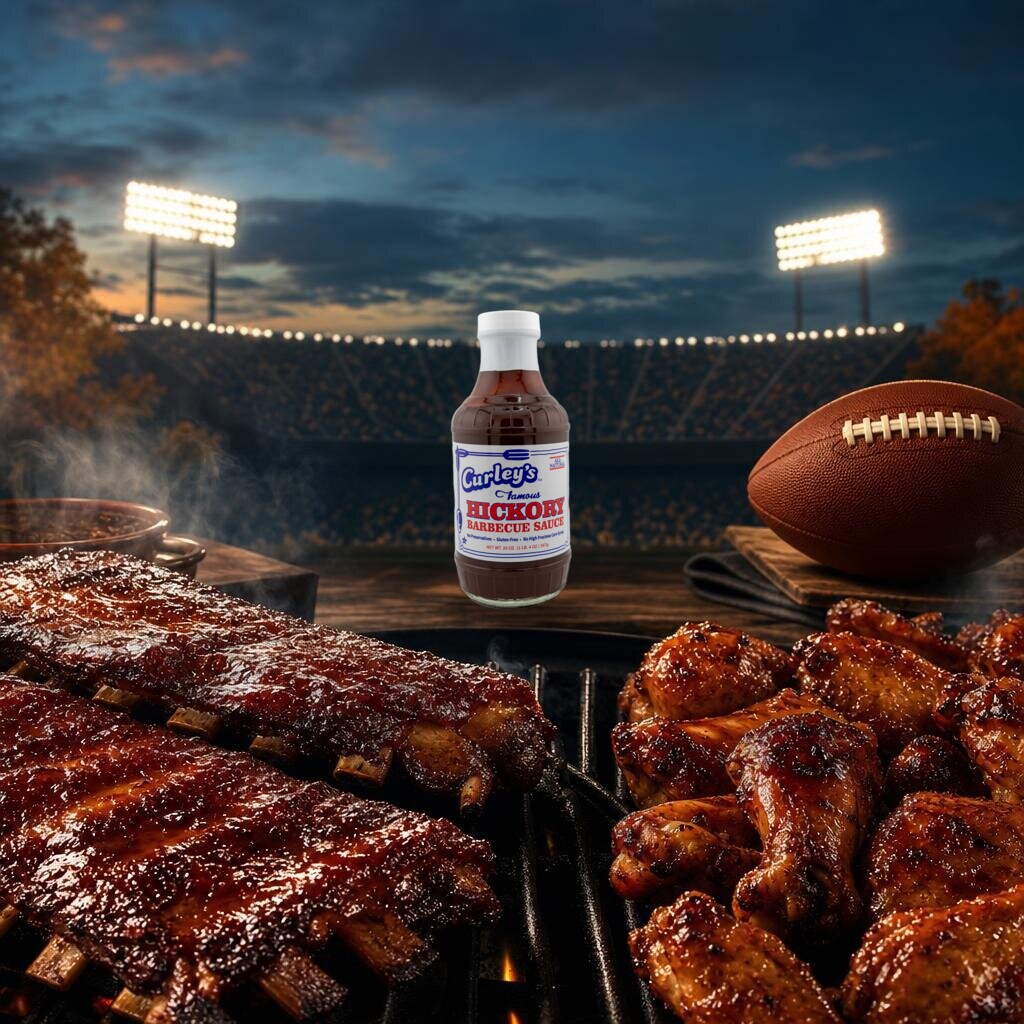 Curley's Famous Hickory BBQ Sauce bottle with glazed ribs, chicken wings, and a football at a stadium tailgate